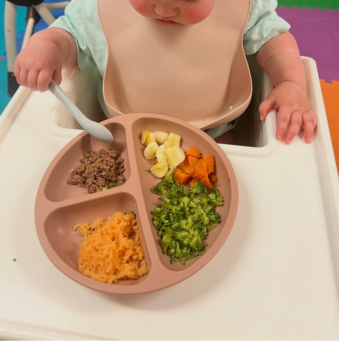 Child sitting in a high chair with a divided plate of food
