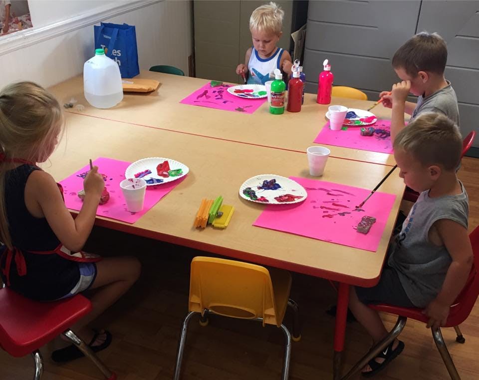 Children painting at a table in a classroom