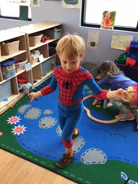 Child in Spider-Man costume standing on a playmat