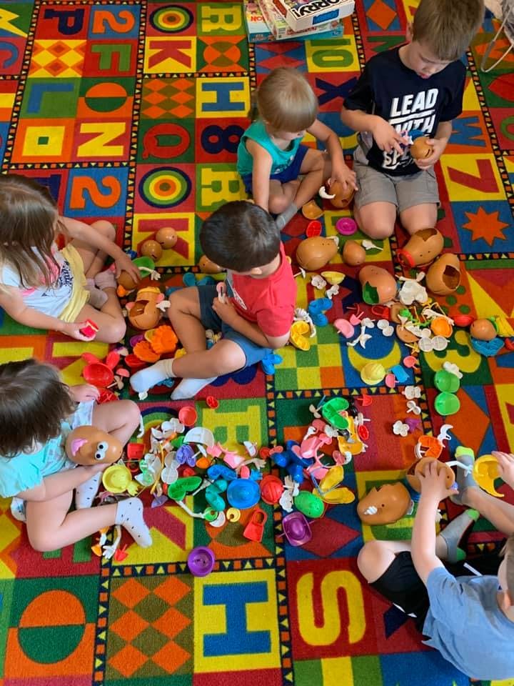 Children playing with toys on a colorful alphabet rug