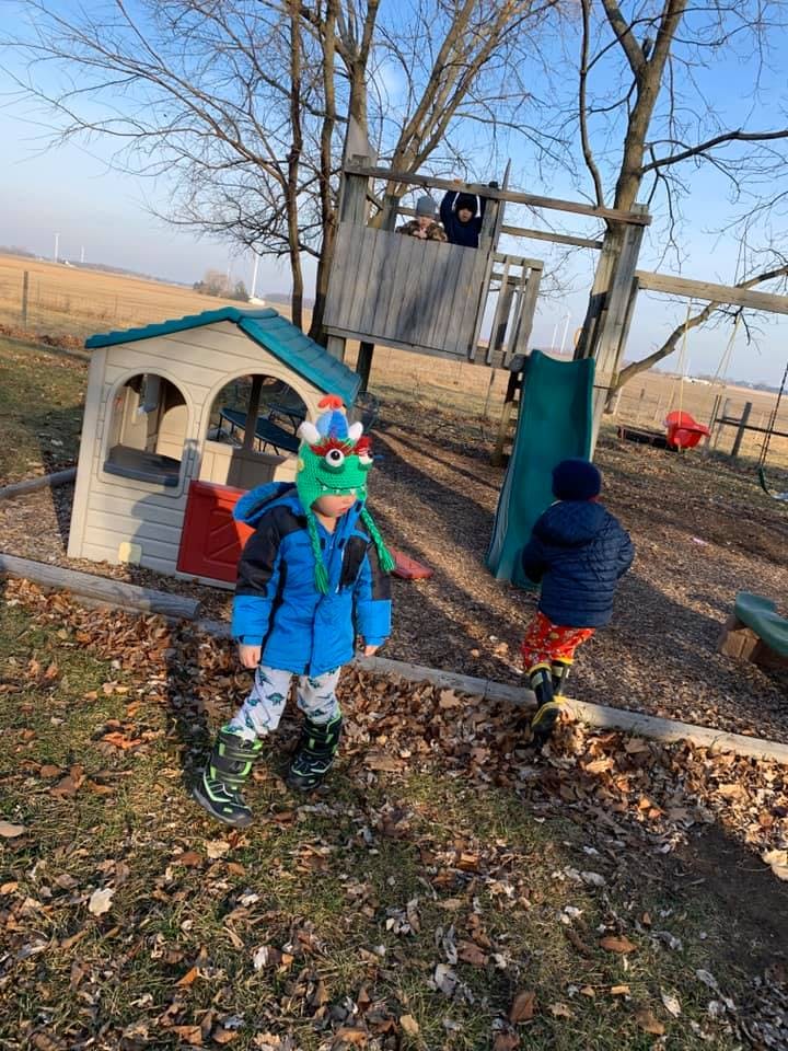 Children playing on a playground with a playhouse and swing set