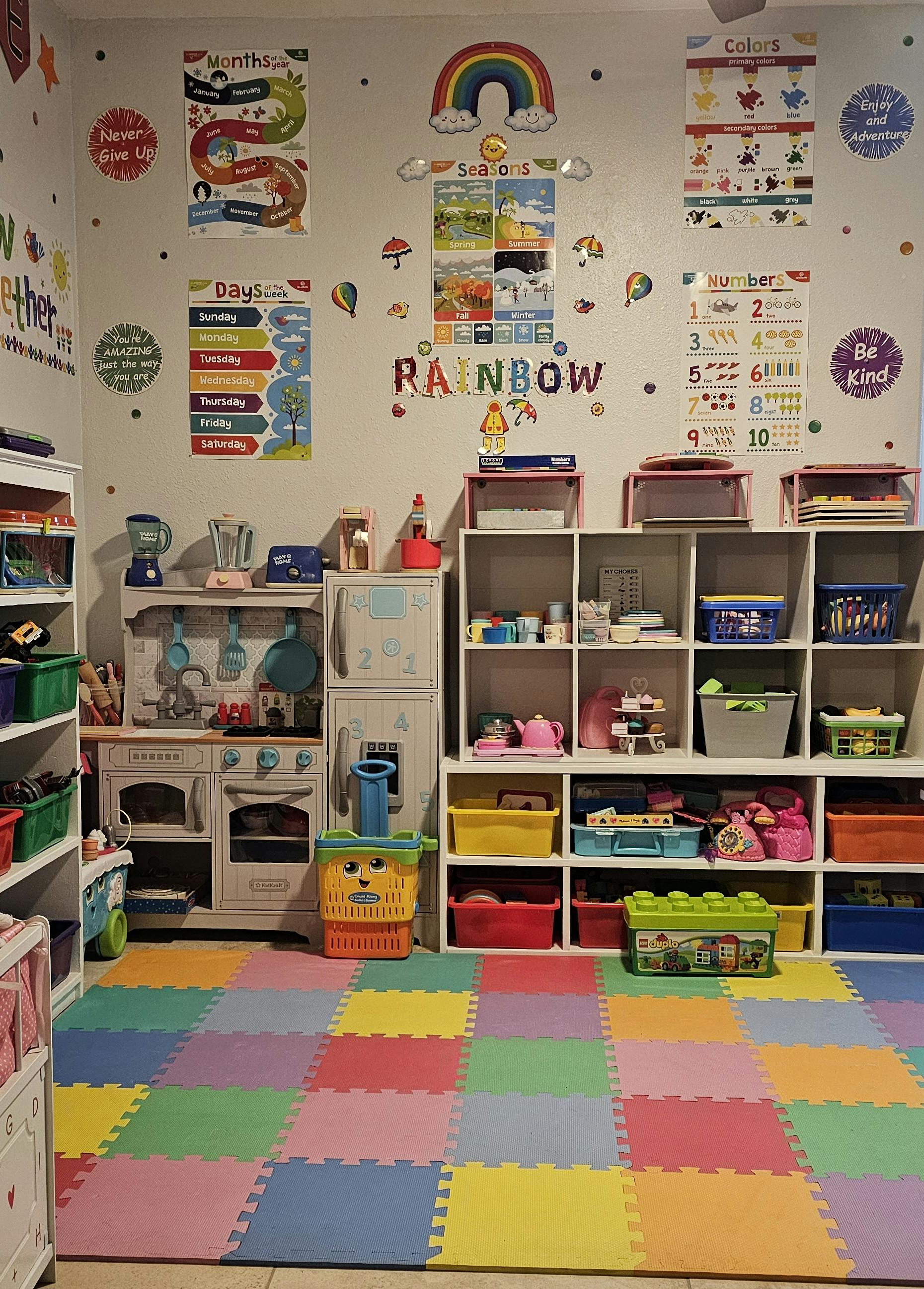 Playroom with colorful floor mats, shelves of toys, and educational wall decorations