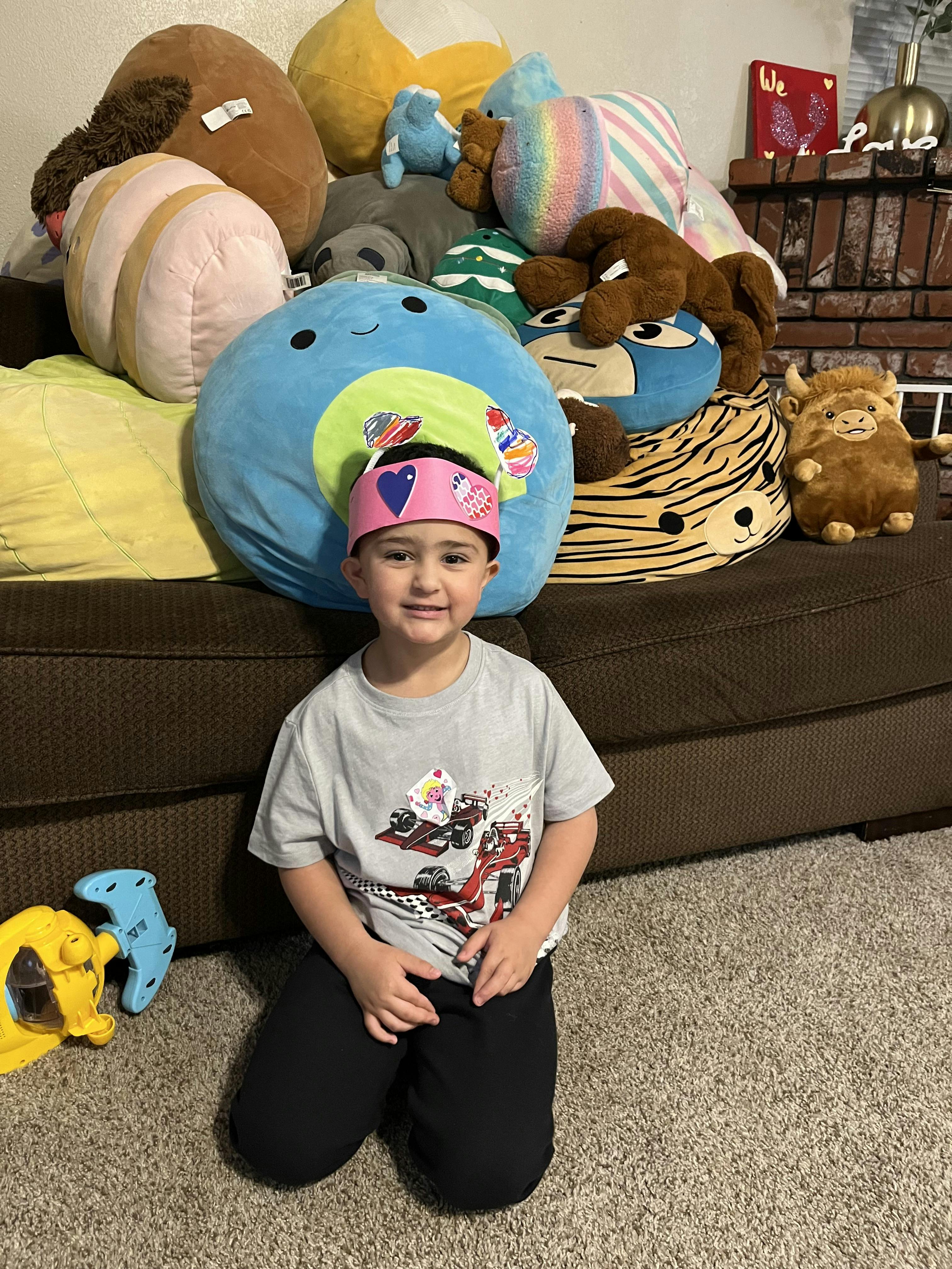 Child kneeling on carpet in front of a couch with stuffed animals
