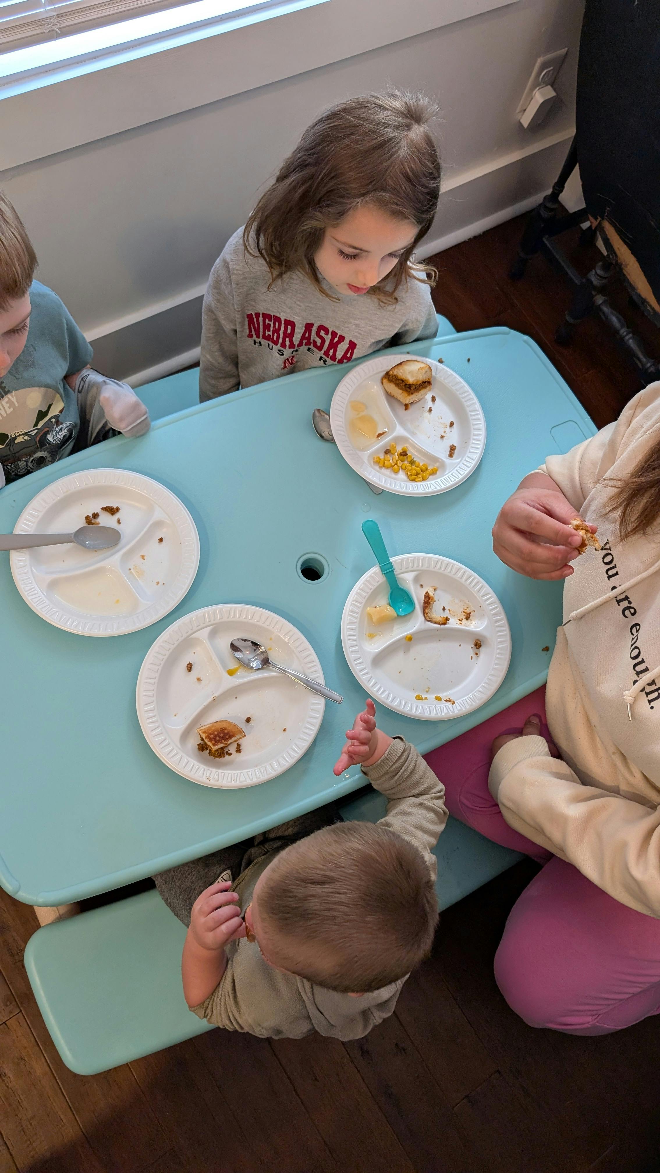 Children eating at a table with plates of food on a blue table