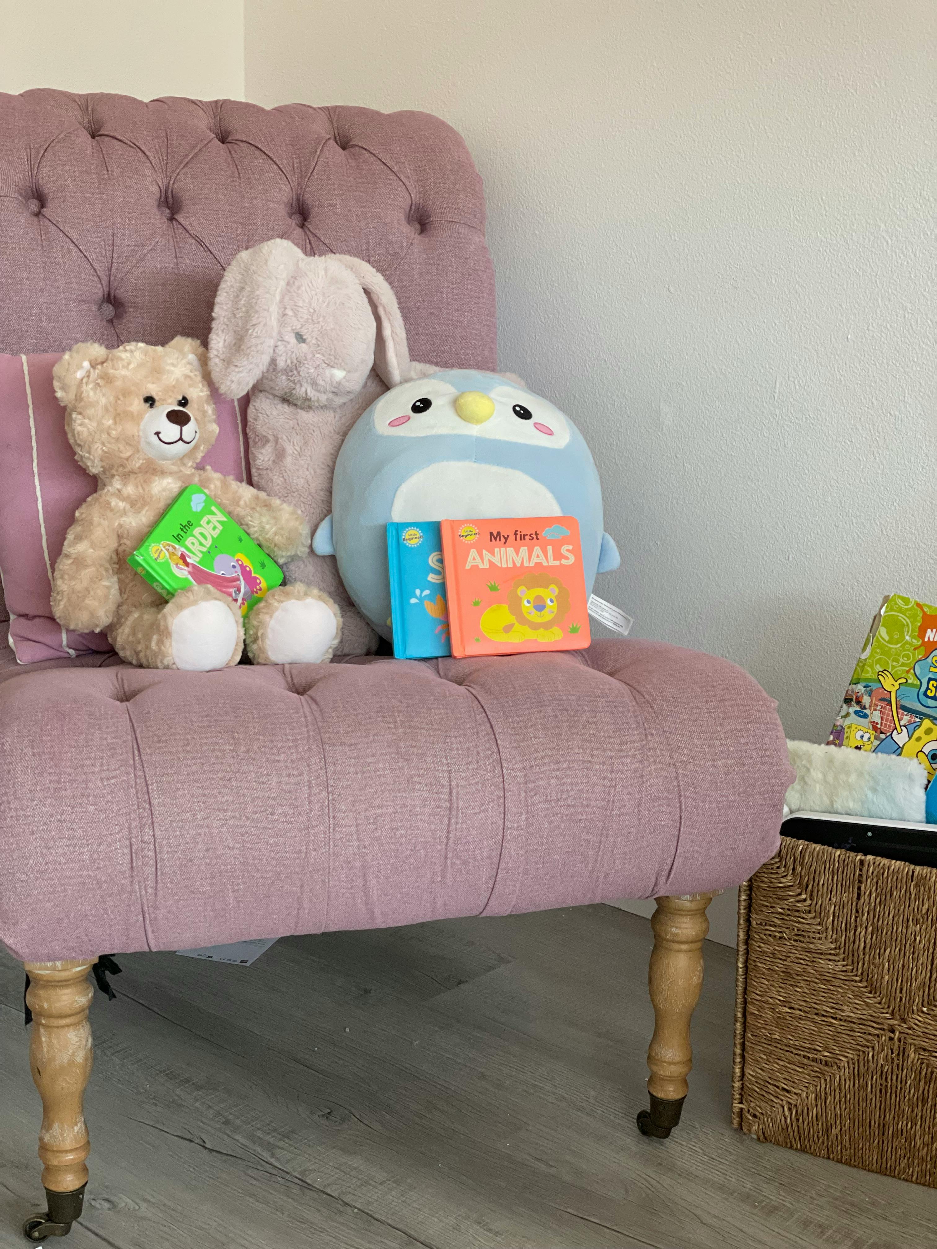 Stuffed animals and children's books on a tufted chair