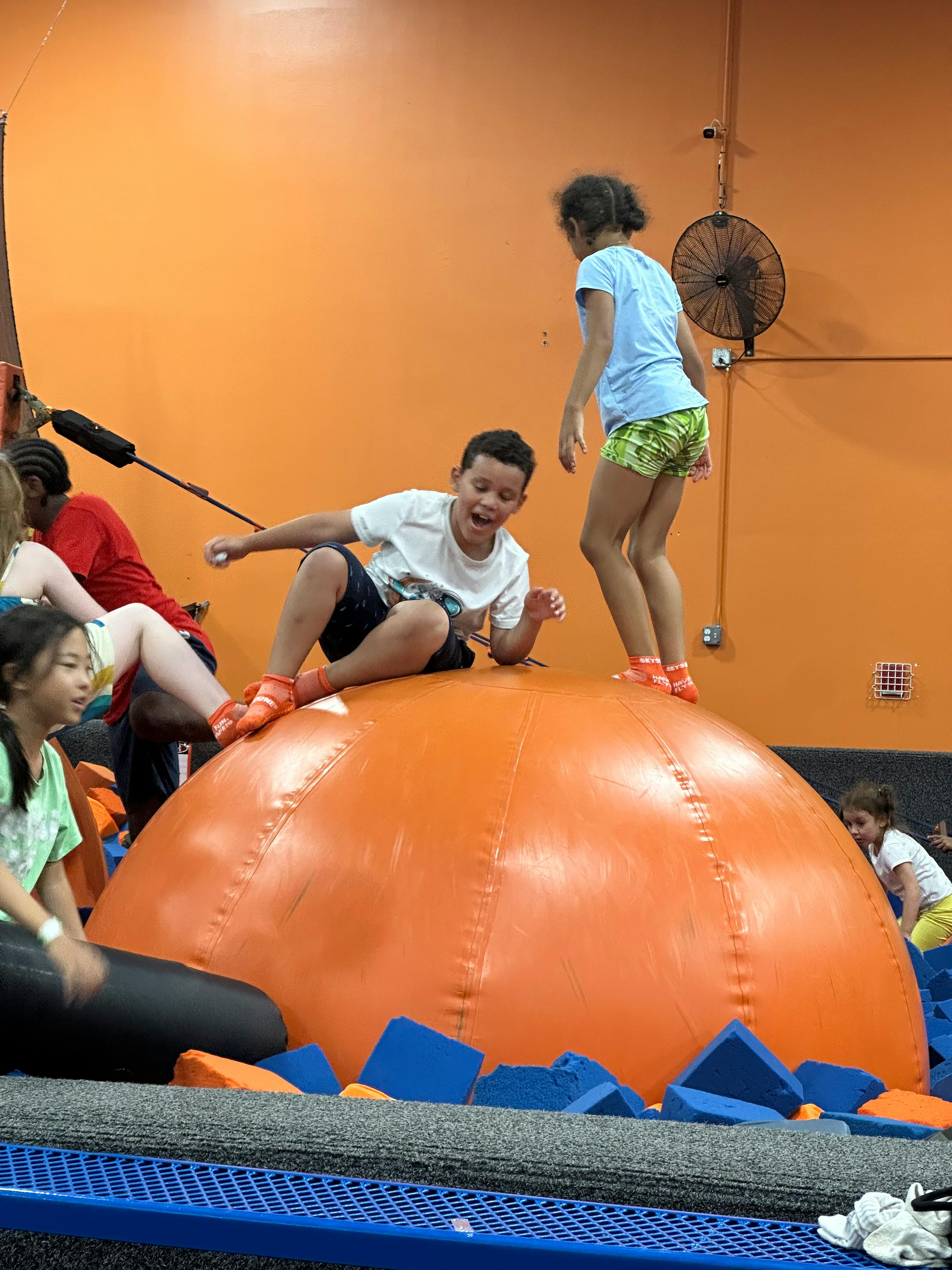 Children playing on an inflatable dome at an indoor trampoline park