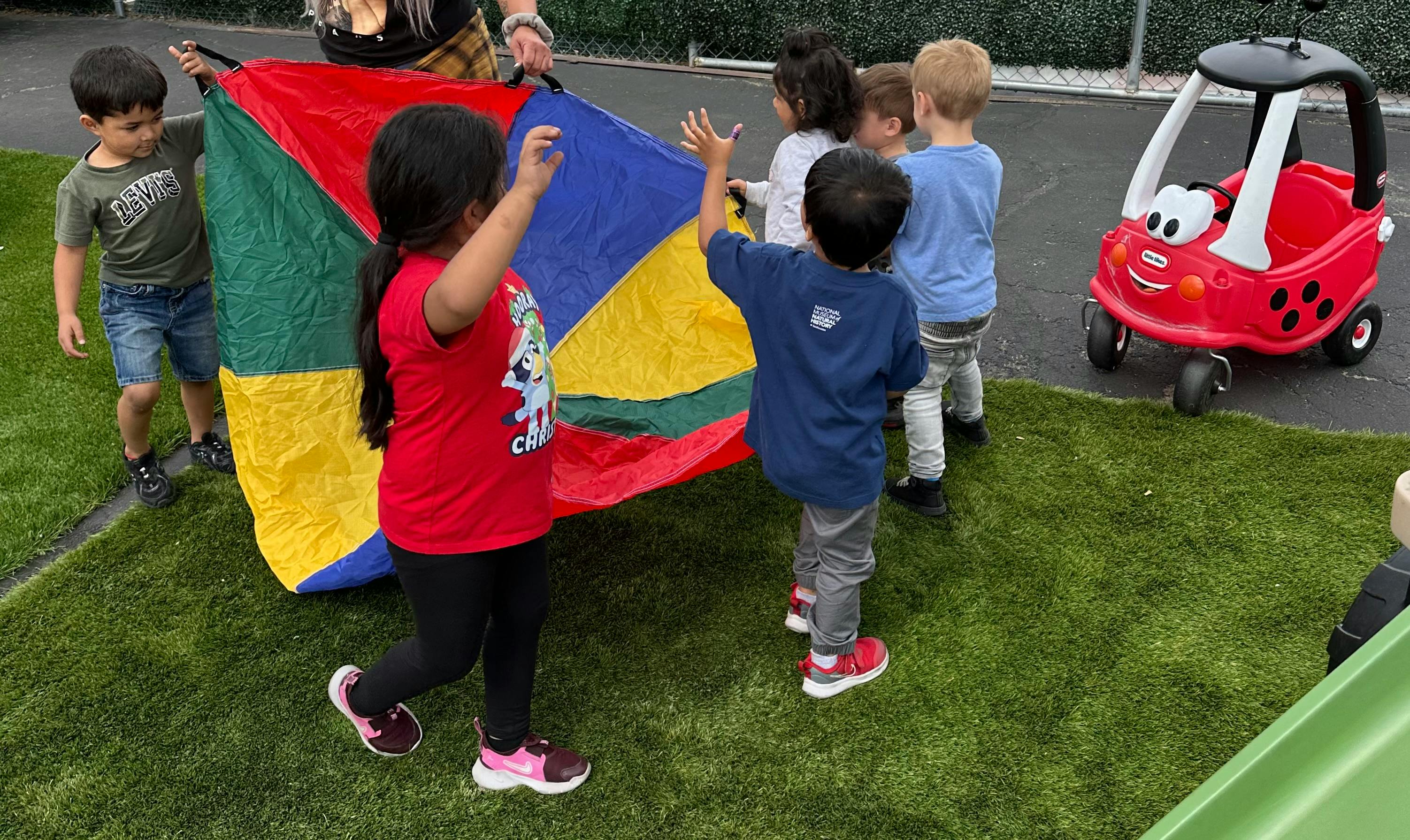 Children playing with a colorful parachute