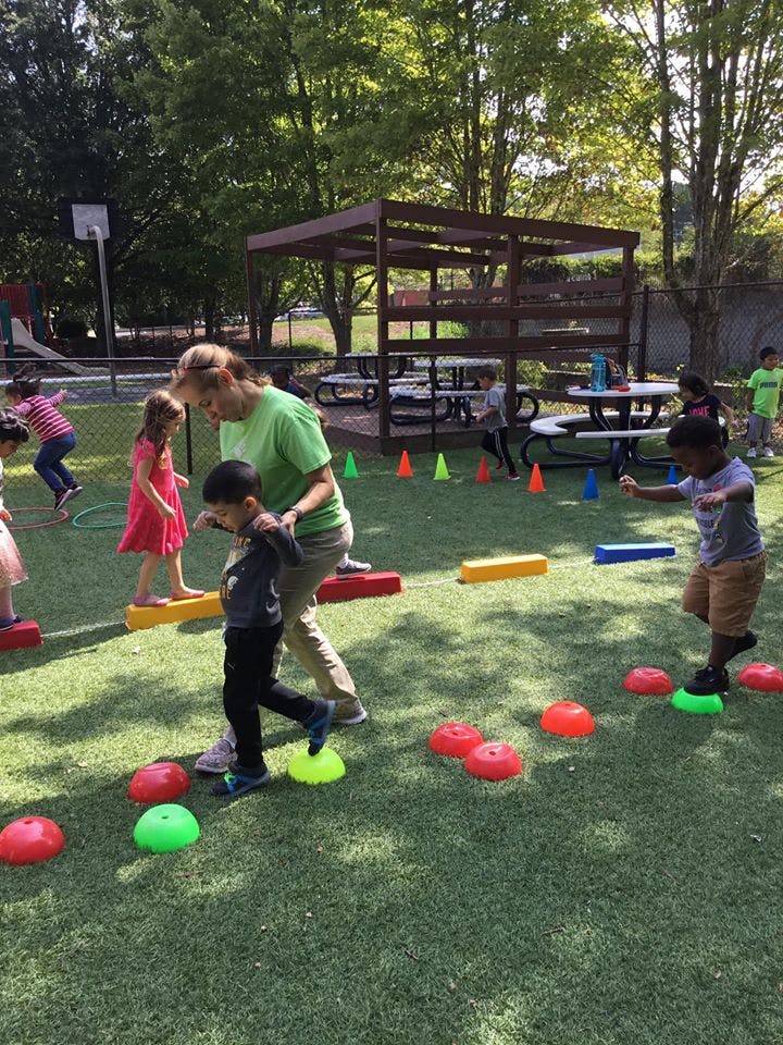 Adult and children playing on balance beams and stepping stones outdoors