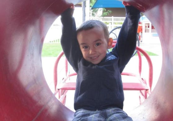 Child in a red tunnel slide with arms raised