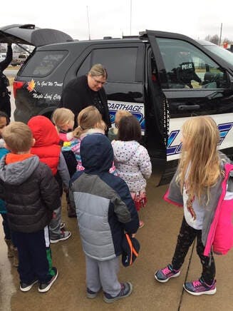 Person in uniform showing children a police vehicle