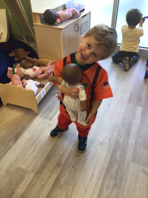 Child holding a doll in a classroom
