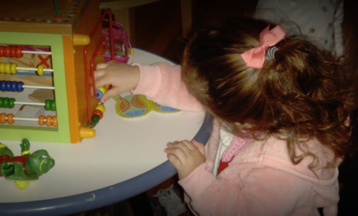 Child playing with an activity cube on a table