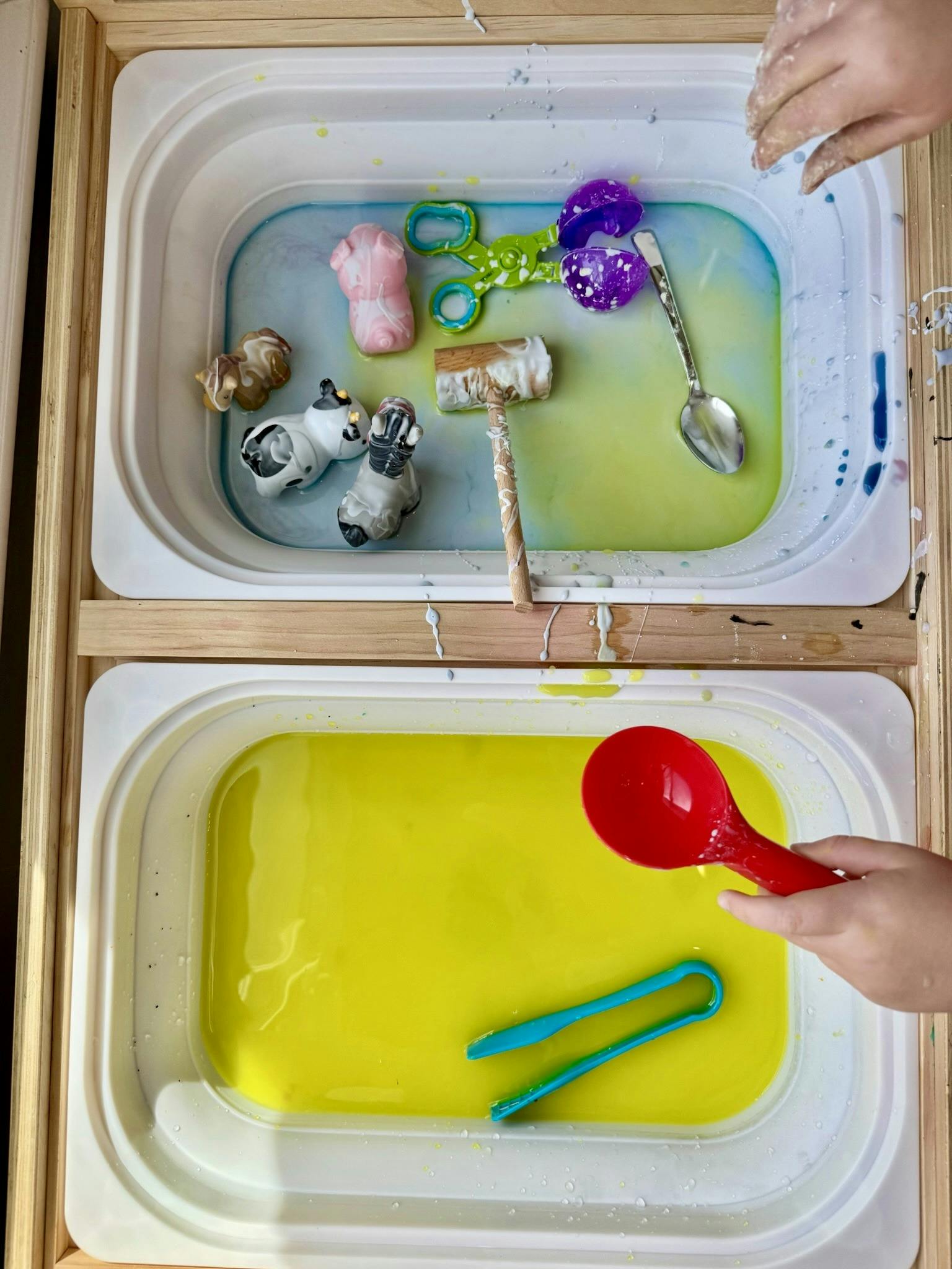 Child playing with toys and utensils in a sensory water table
