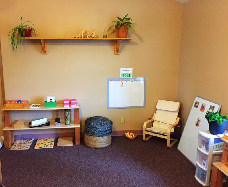 Classroom with shelves, whiteboard, chair, and ottoman