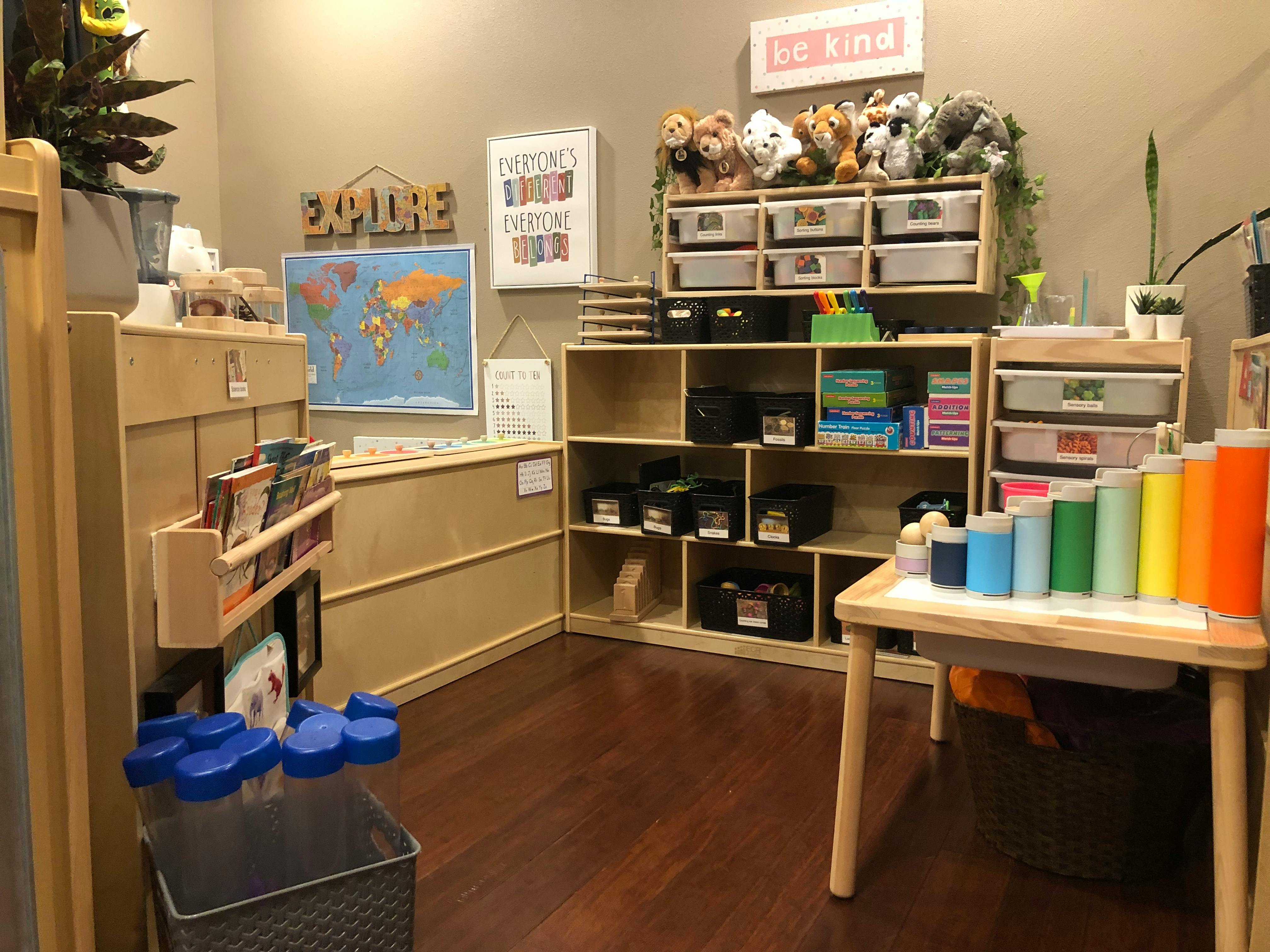 Classroom with shelves, a world map, and a table with colorful cylinders