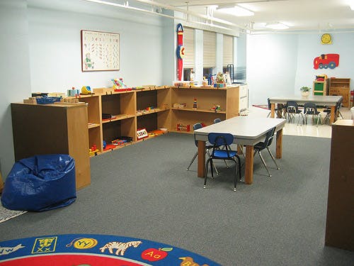 Classroom with shelves, tables, chairs, and a blue beanbag chair