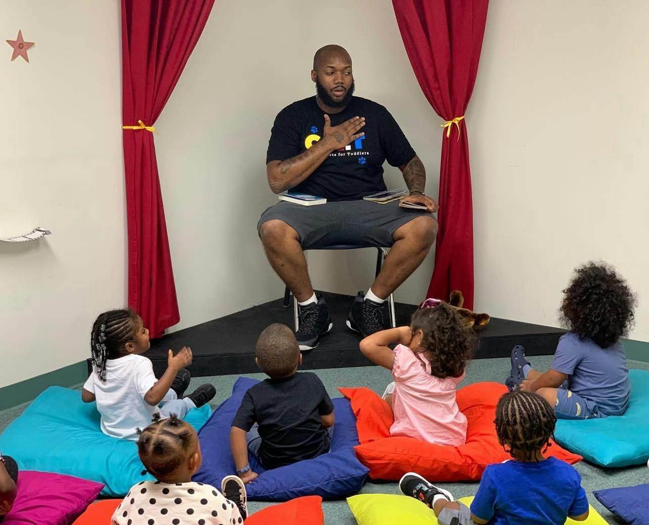 Adult sitting in front of several children on floor cushions