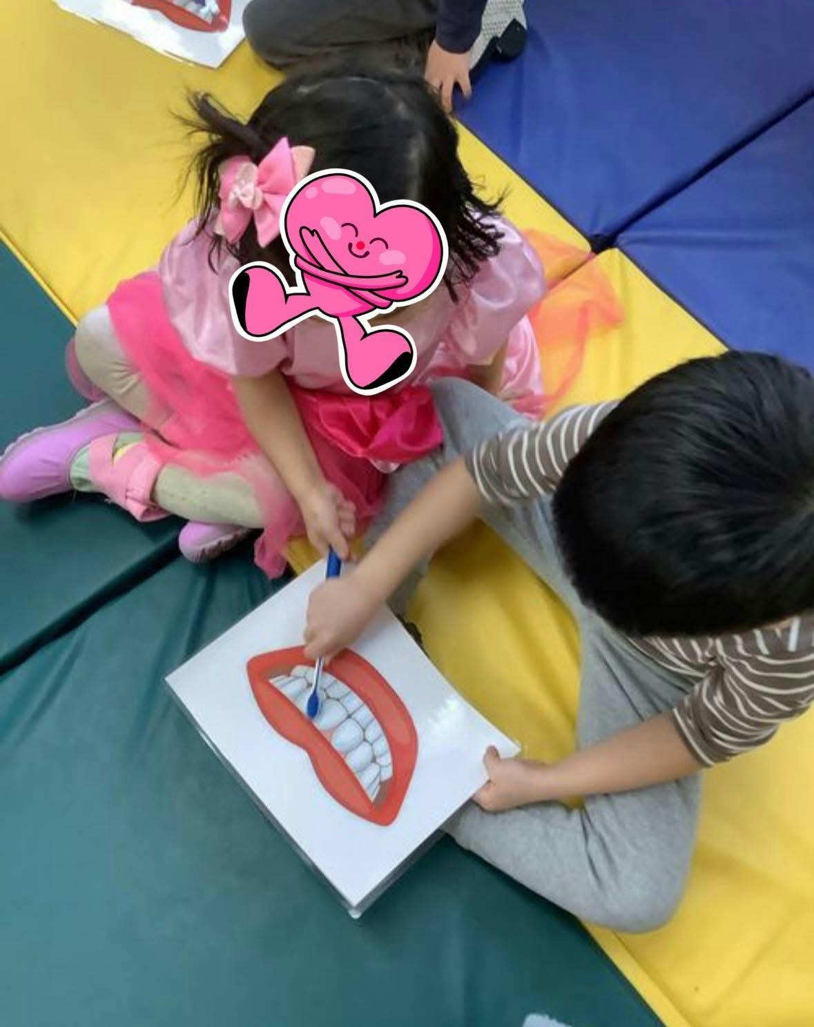 Child brushing a large mouth and teeth diagram with a toothbrush