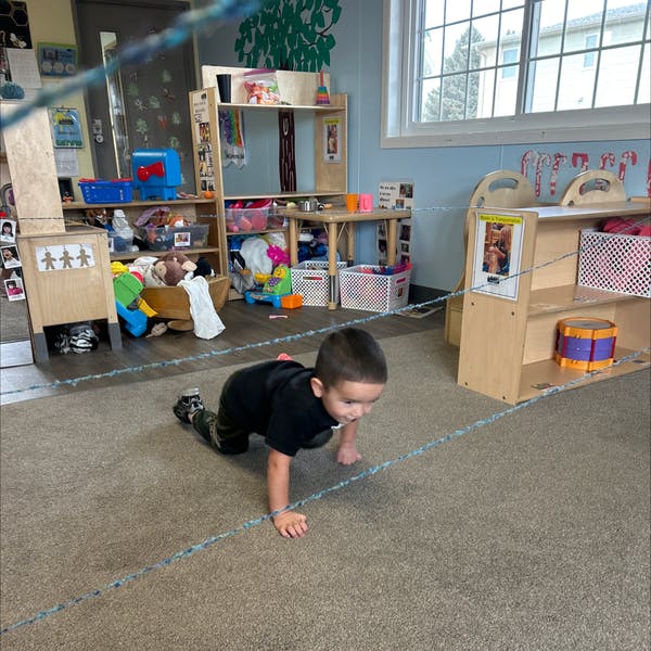 Child crawling on a carpeted floor in a classroom