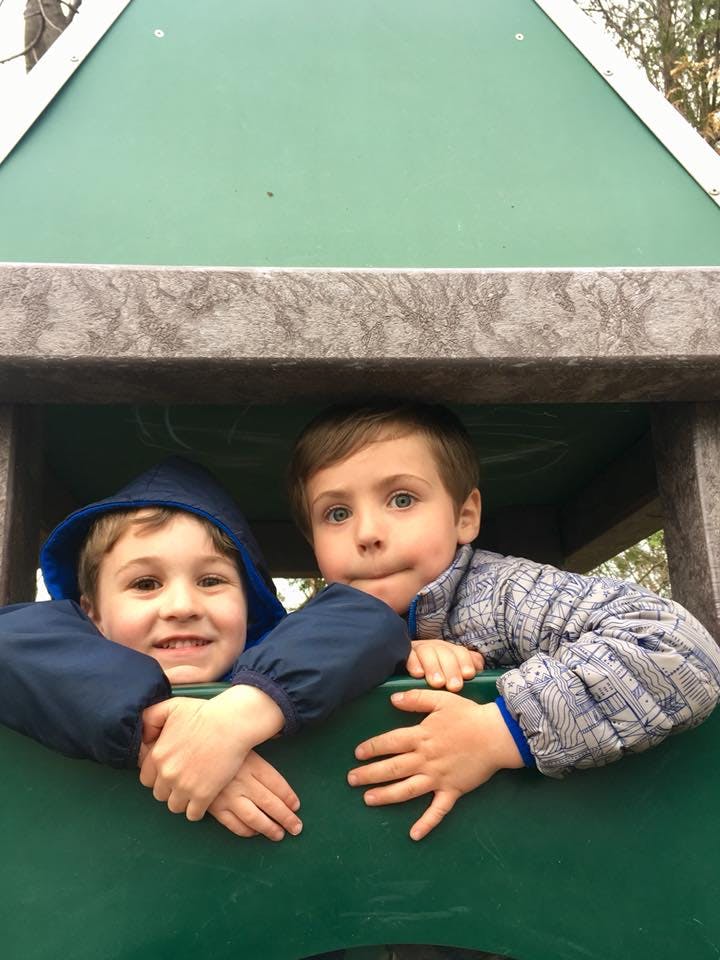 Two children looking out from a green play structure
