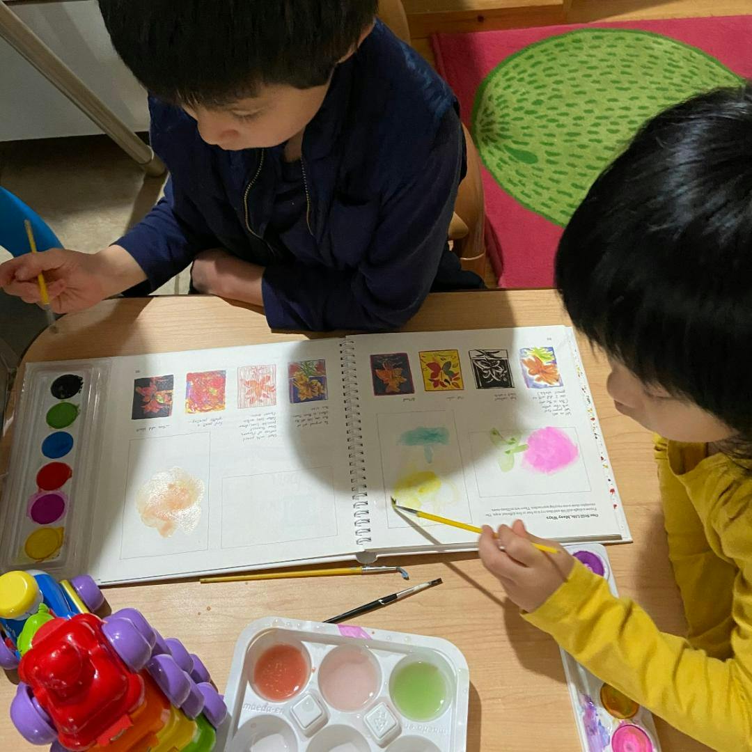 Two children painting in a book with watercolors