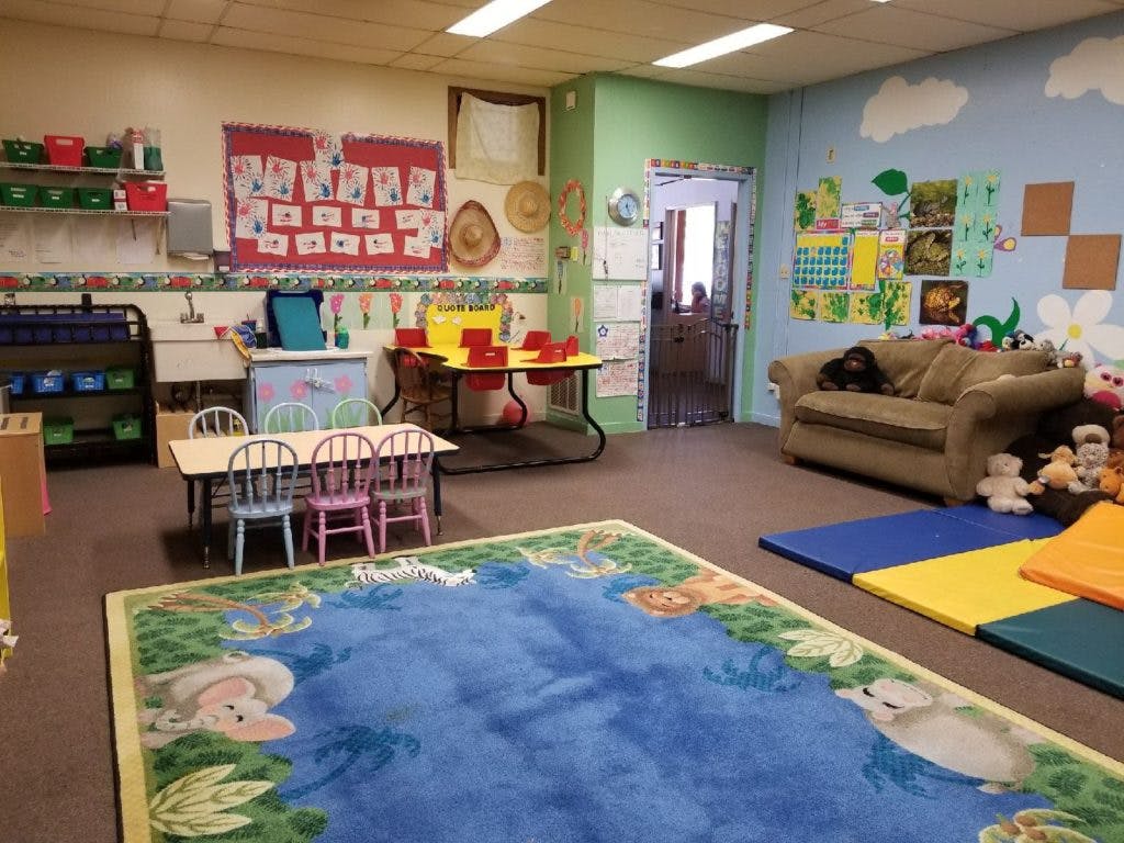 Playroom with small tables and chairs, a sofa, and a blue rug