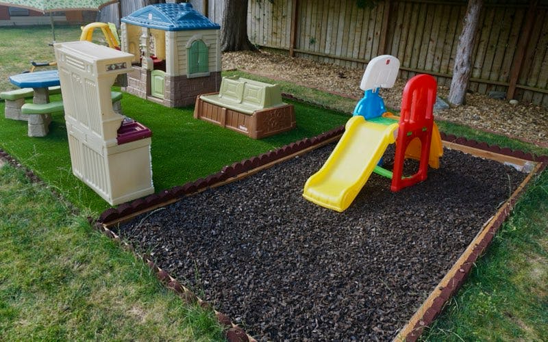 Outdoor play area with artificial turf, playhouse, picnic table, and slide