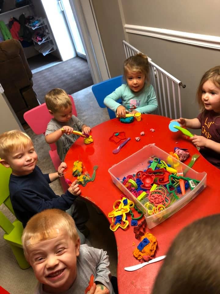 Children playing with colorful toys at a red table