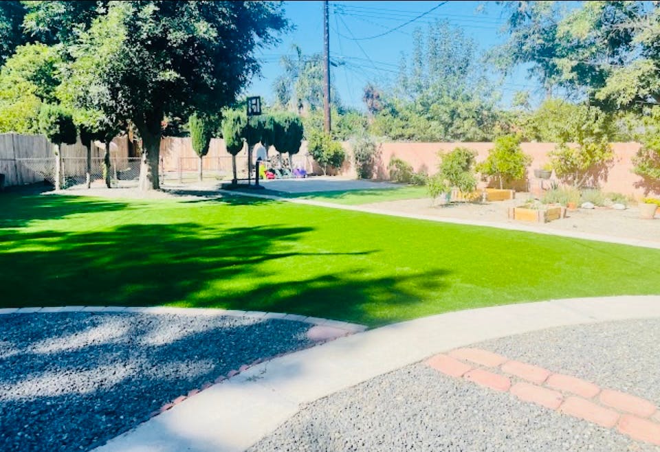 Outdoor area with green grass, trees, and a gravel path