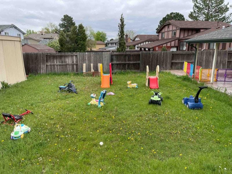 Backyard with various children's toys and play equipment on grass