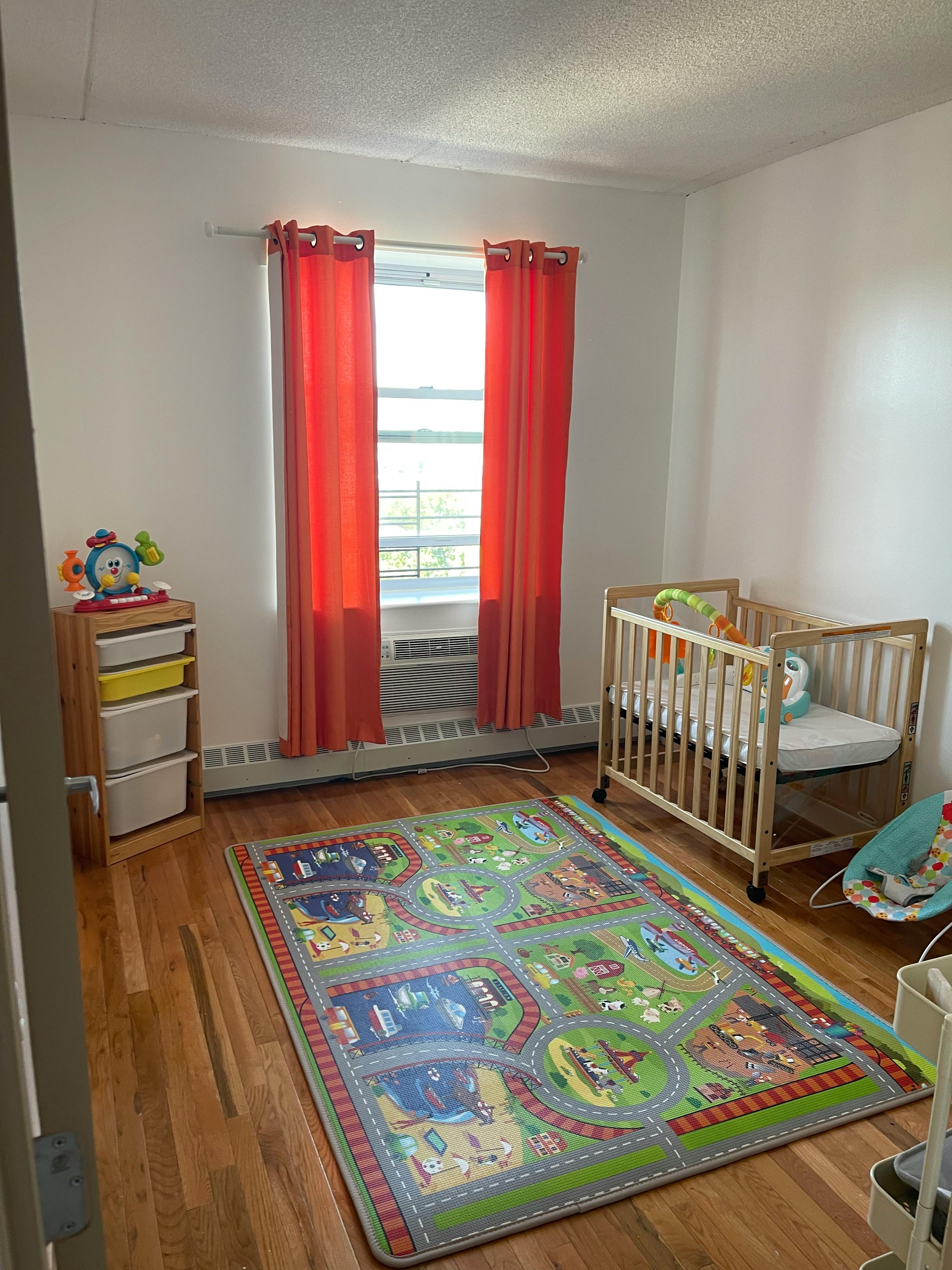Nursery room with a crib, storage unit, and play mat
