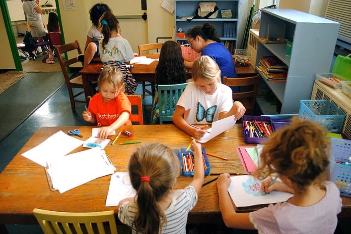 Children drawing and coloring at a table in a classroom