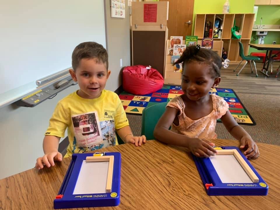 Two children at a table with drawing boards in a classroom