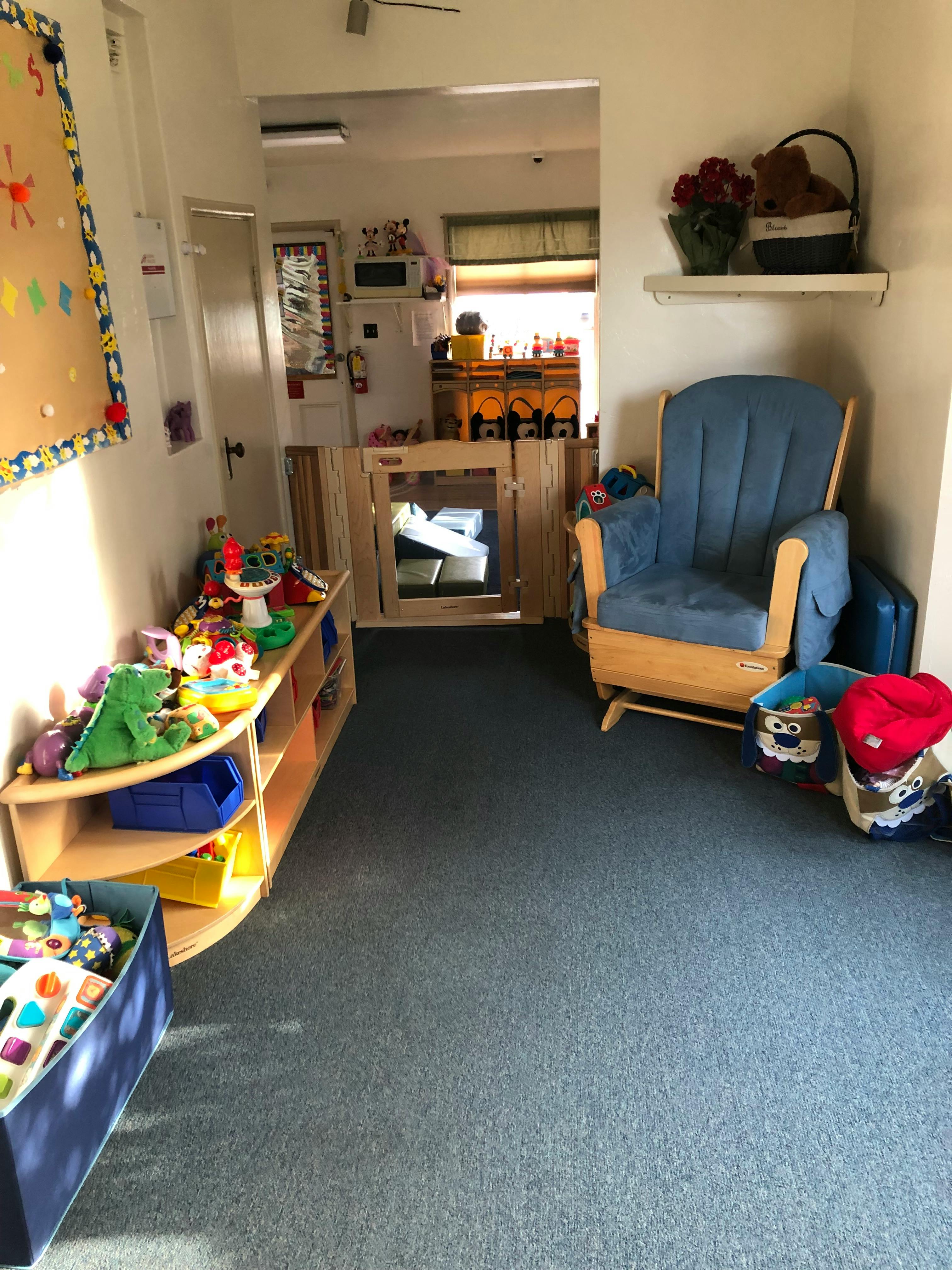 Playroom with toys on shelves and a blue rocking chair