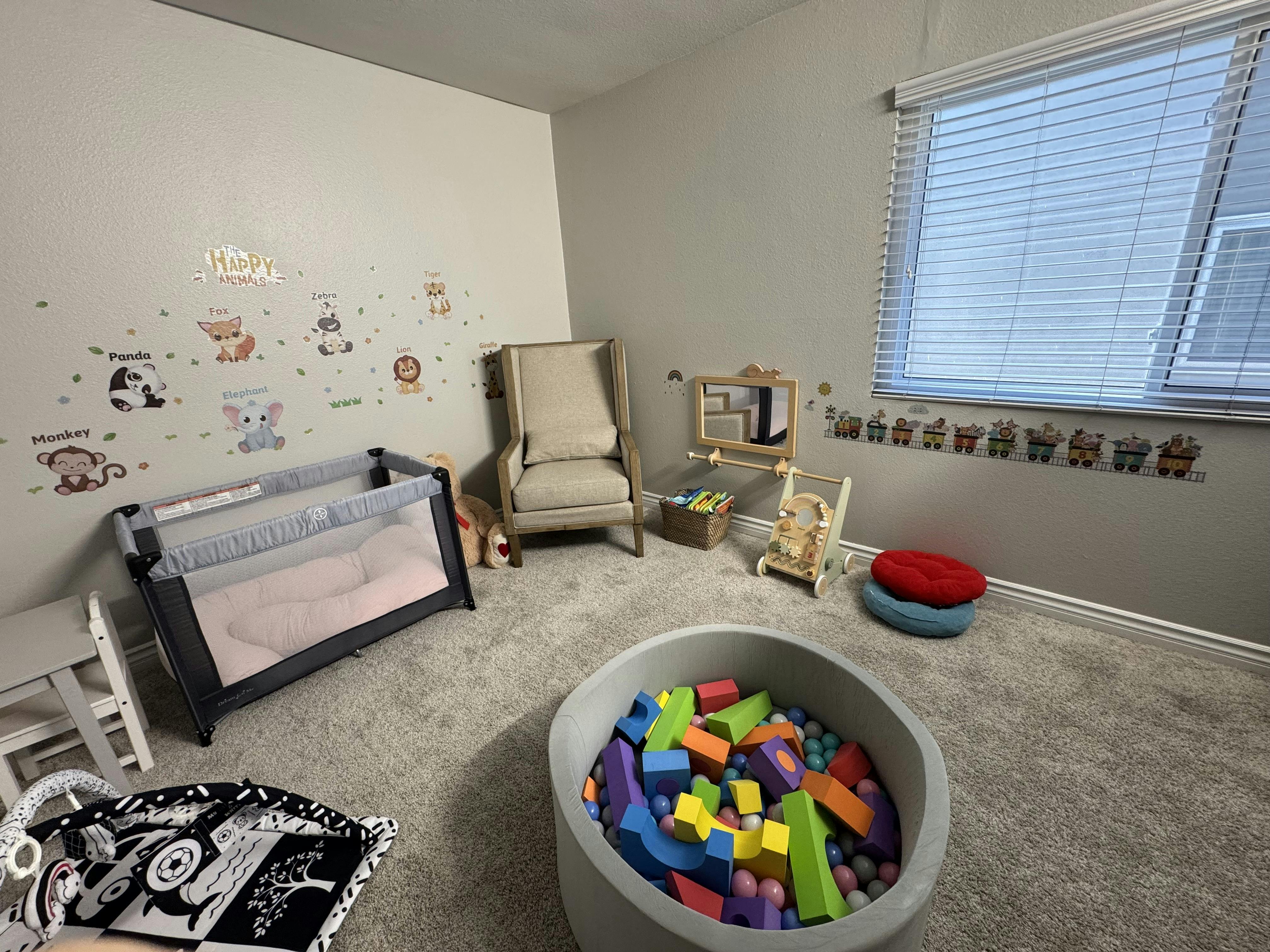 Child playroom with playpen, armchair, and ball pit filled with foam blocks