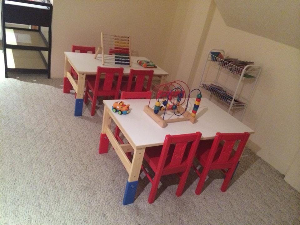 Two small tables with red chairs and toys in a room with toys