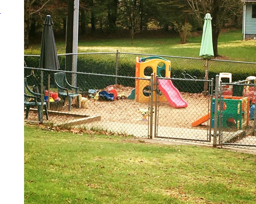 Playground with a slide and sandbox behind a chain link fence