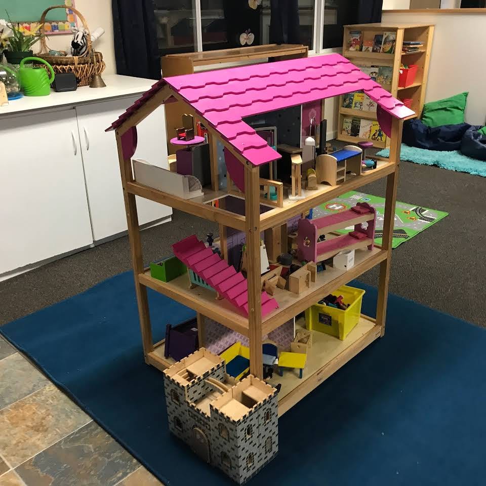 Dollhouse with pink roof and furniture in a room