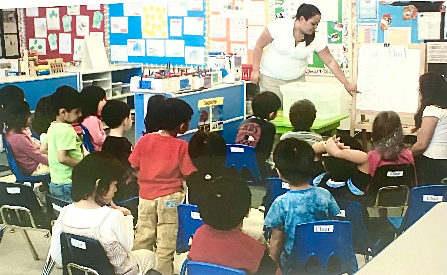 Teacher demonstrating a sink or float experiment to a class of children