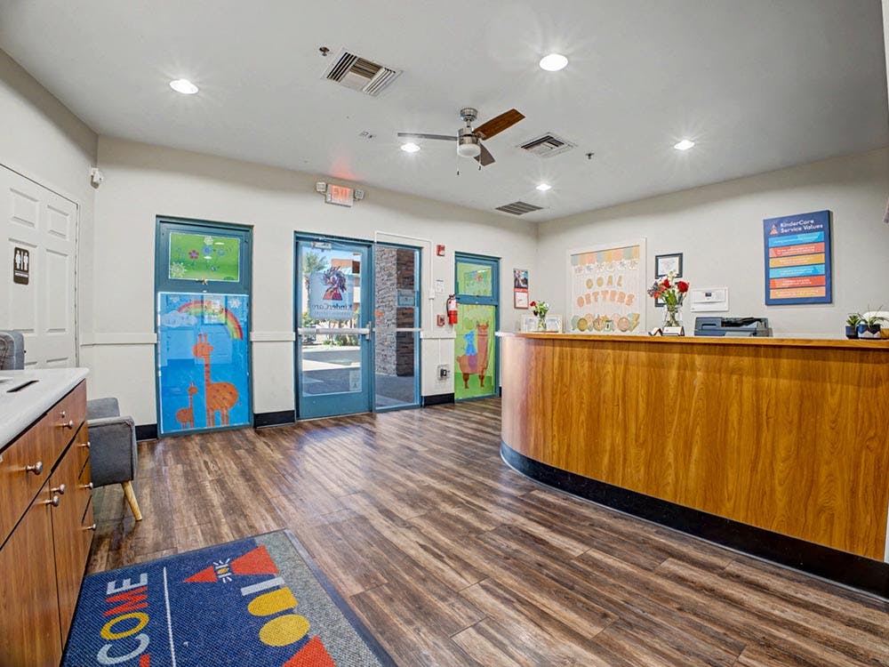 Reception area with a wooden counter and entrance doors with colorful decorations