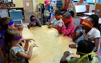 Children blindfolded at a table