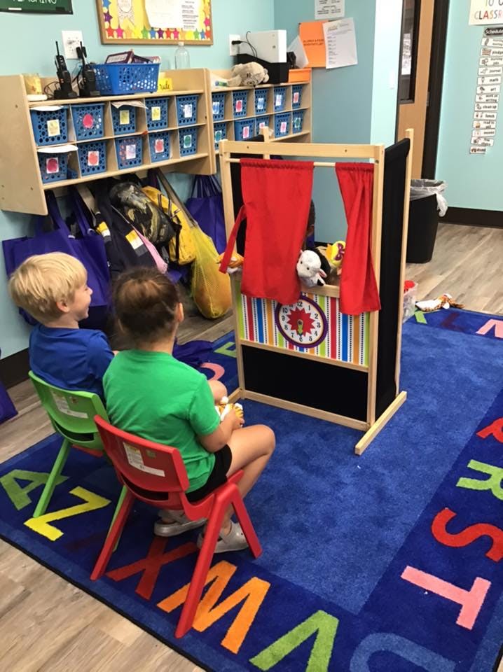 Two children sitting in front of a puppet theater