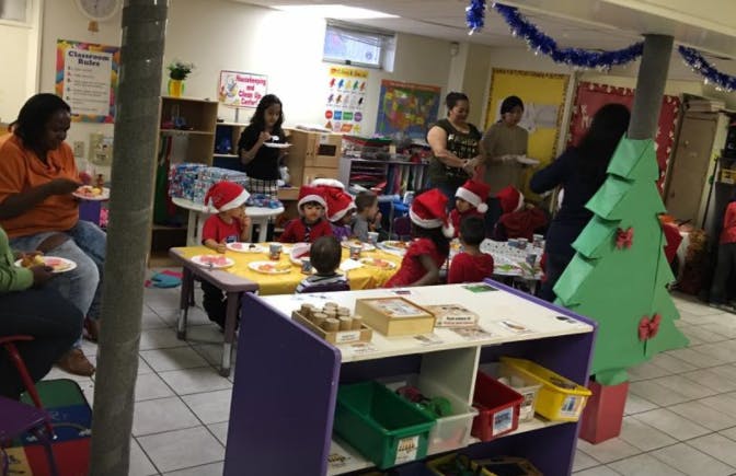 People and children in Santa hats eating at tables in a classroom