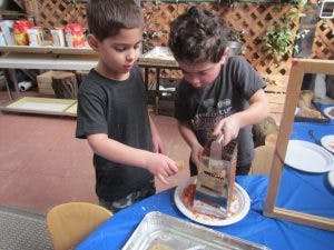 Two children grating food onto a plate