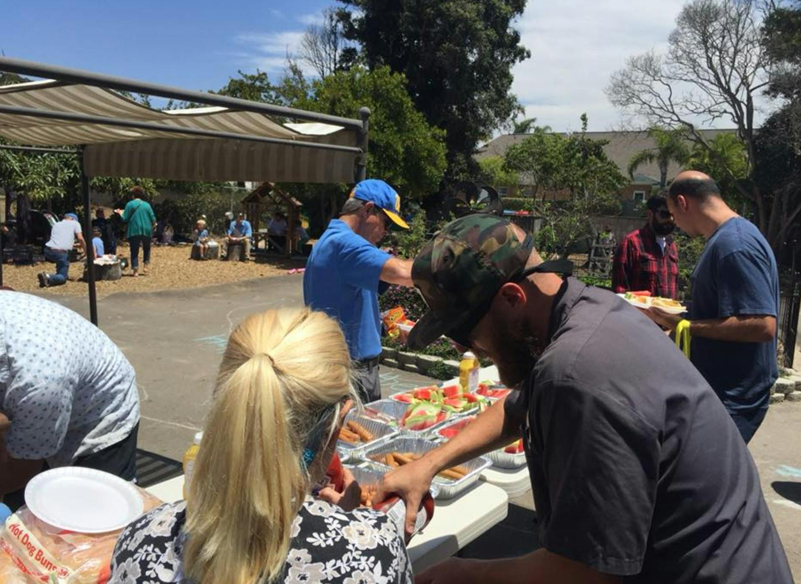 People serving themselves food from a buffet line outdoors