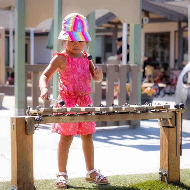 Child playing a xylophone on a playground