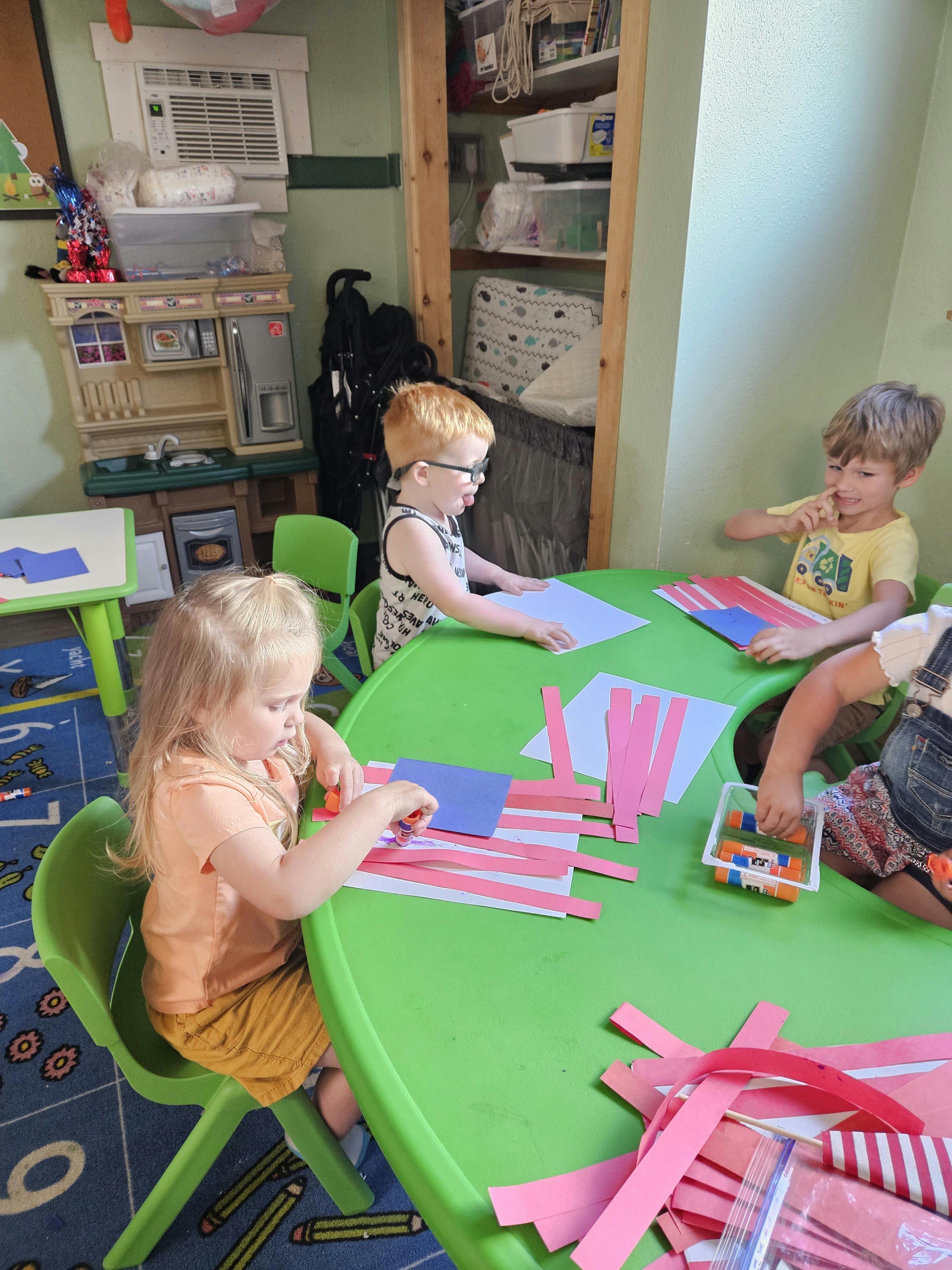 Children sitting at a table doing crafts with paper crafts