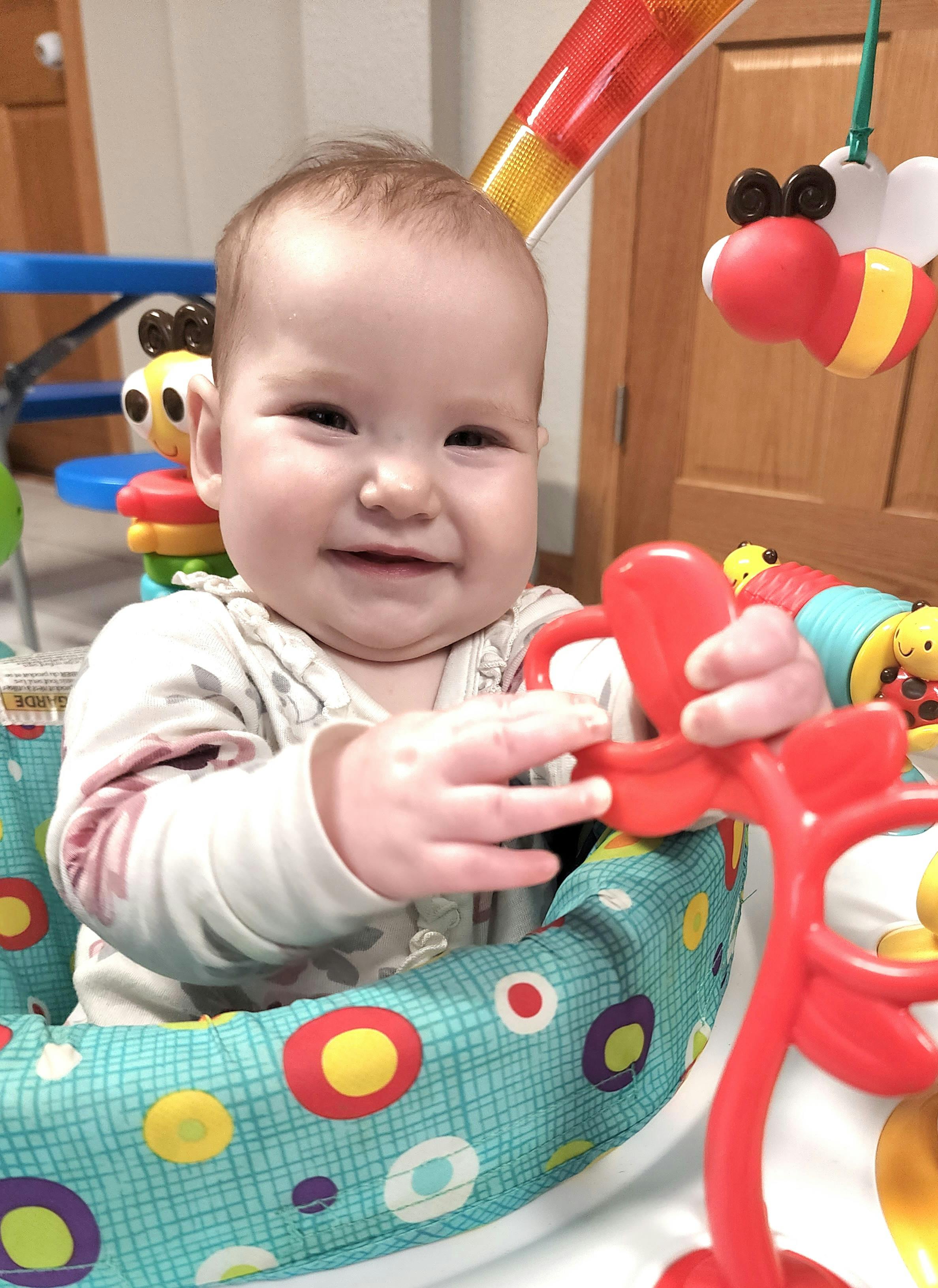 Child in a baby activity center playing with a red toy
