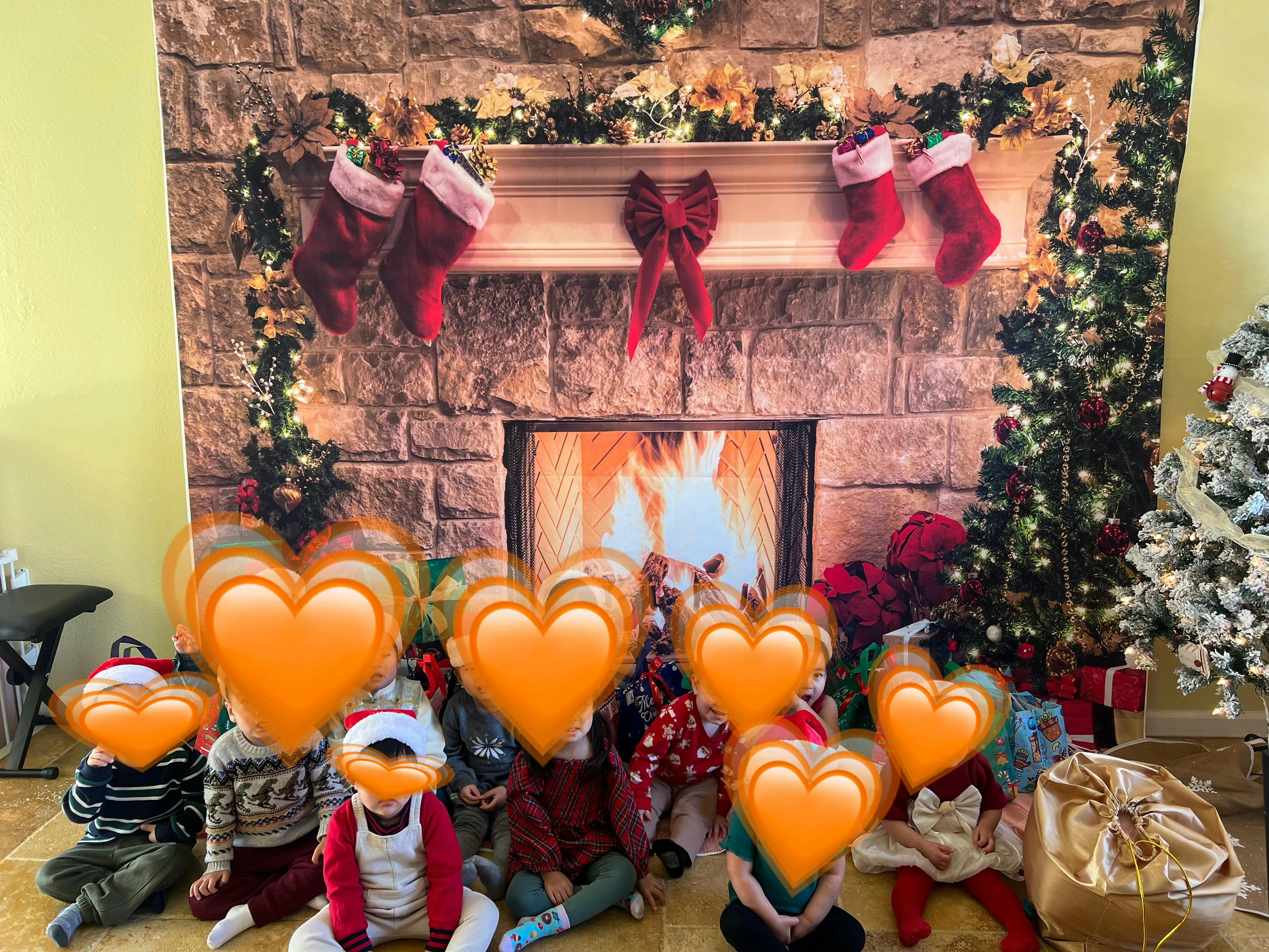 Group of children sitting on the floor in front of a fireplace backdrop