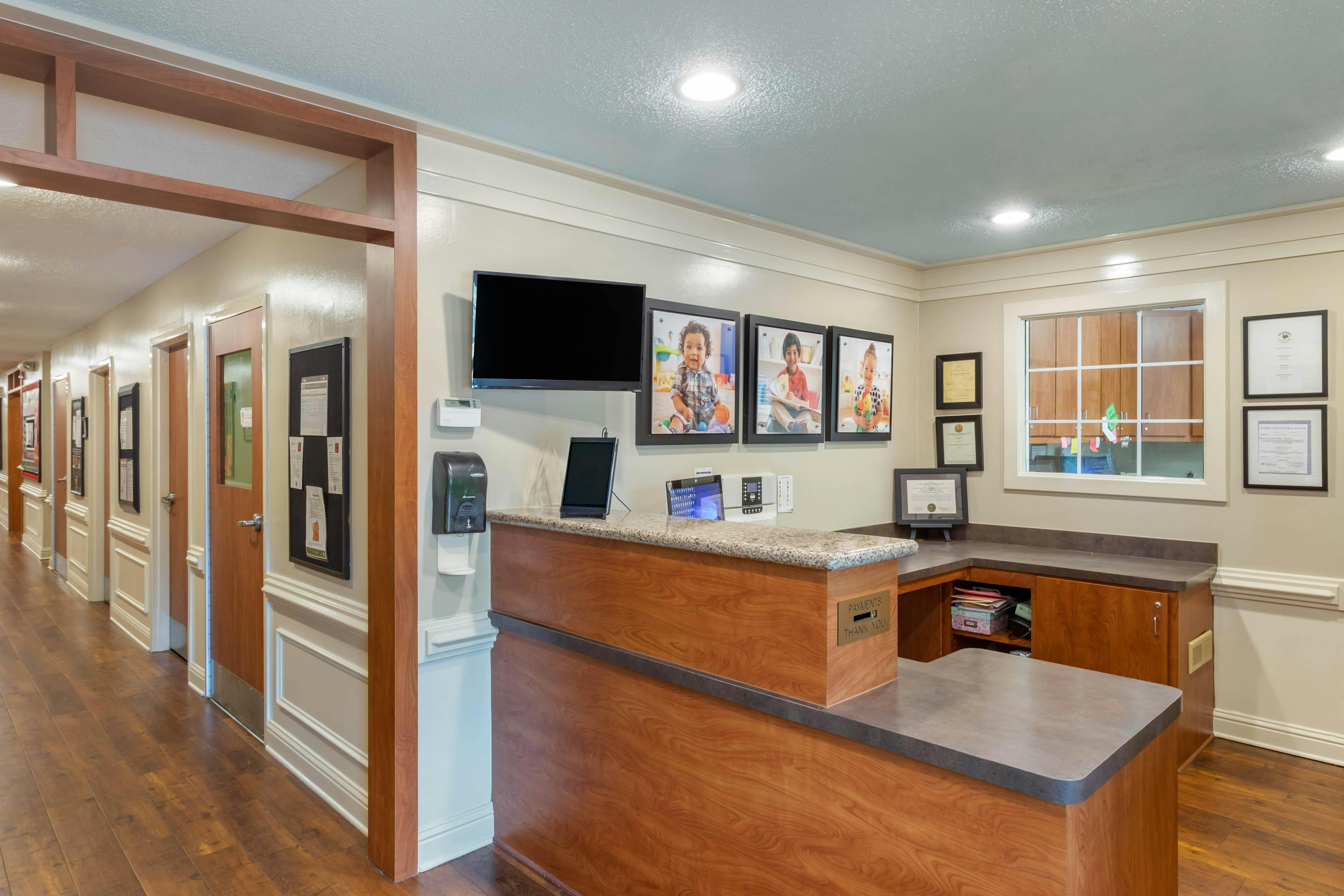 Reception desk with tablets and a television above, next to a hallway with multiple doors